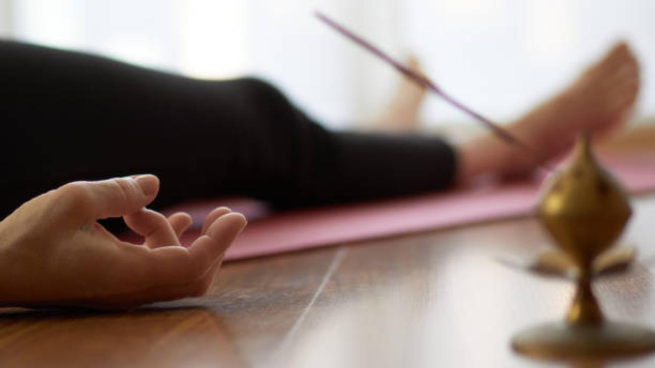 woman practicing yoga, lying in yoga nidra pose, exercise in Shavasana, exercises, work, rest after practice, female hand. Healthy lifestyle concept