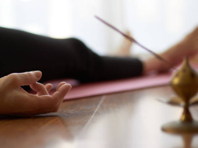 woman practicing yoga, lying in yoga nidra pose, exercise in Shavasana, exercises, work, rest after practice, female hand. Healthy lifestyle concept